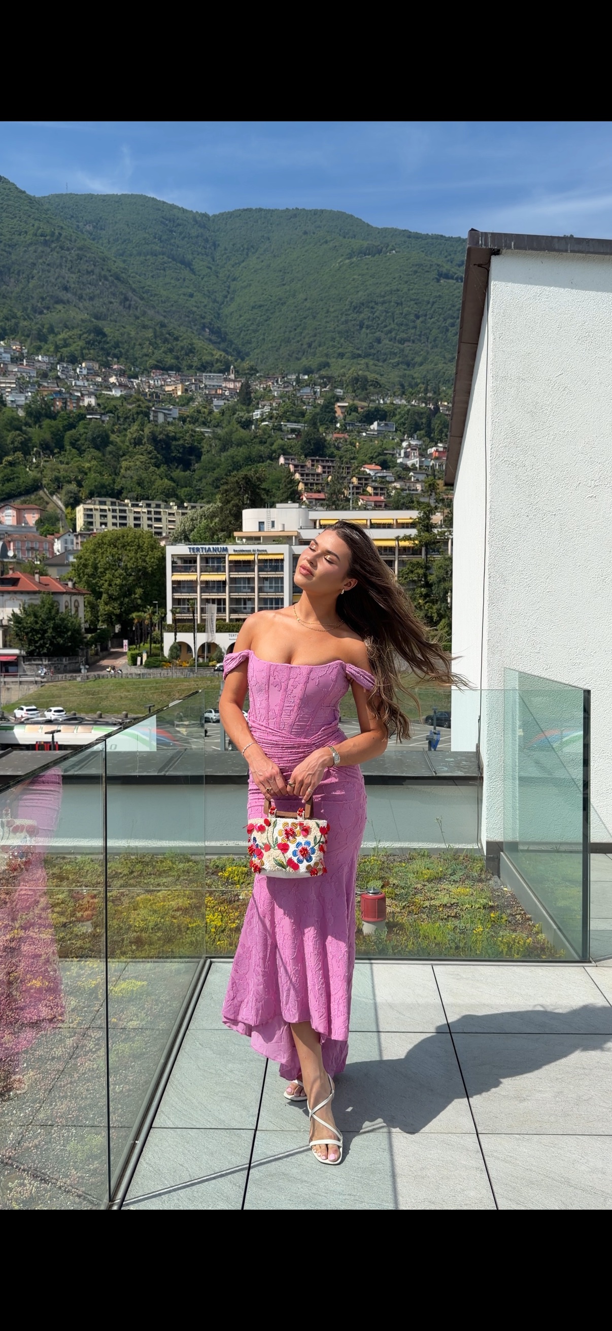 Jess in a lilac dress on a terrace overlooking the mountains