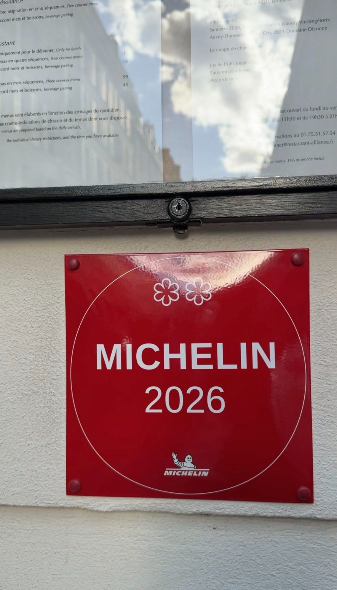 Michelin 2026 plaque outside Restaurant Alliance in Paris, under the menu posted in the window