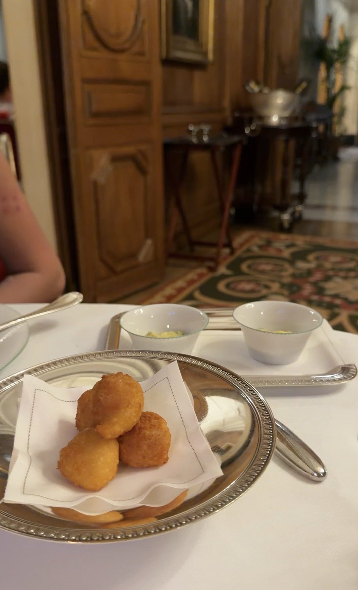 Three fried beignets on a silver tray with two bowls of sauce at Le Clarence