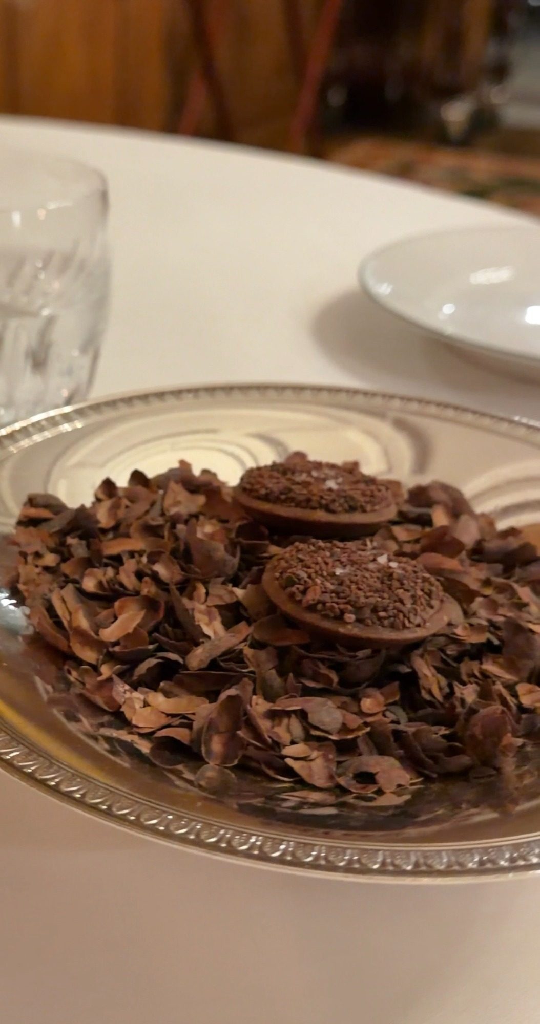 Chocolate rounds on a bed of cocoa nibs in a silver dish at Le Clarence