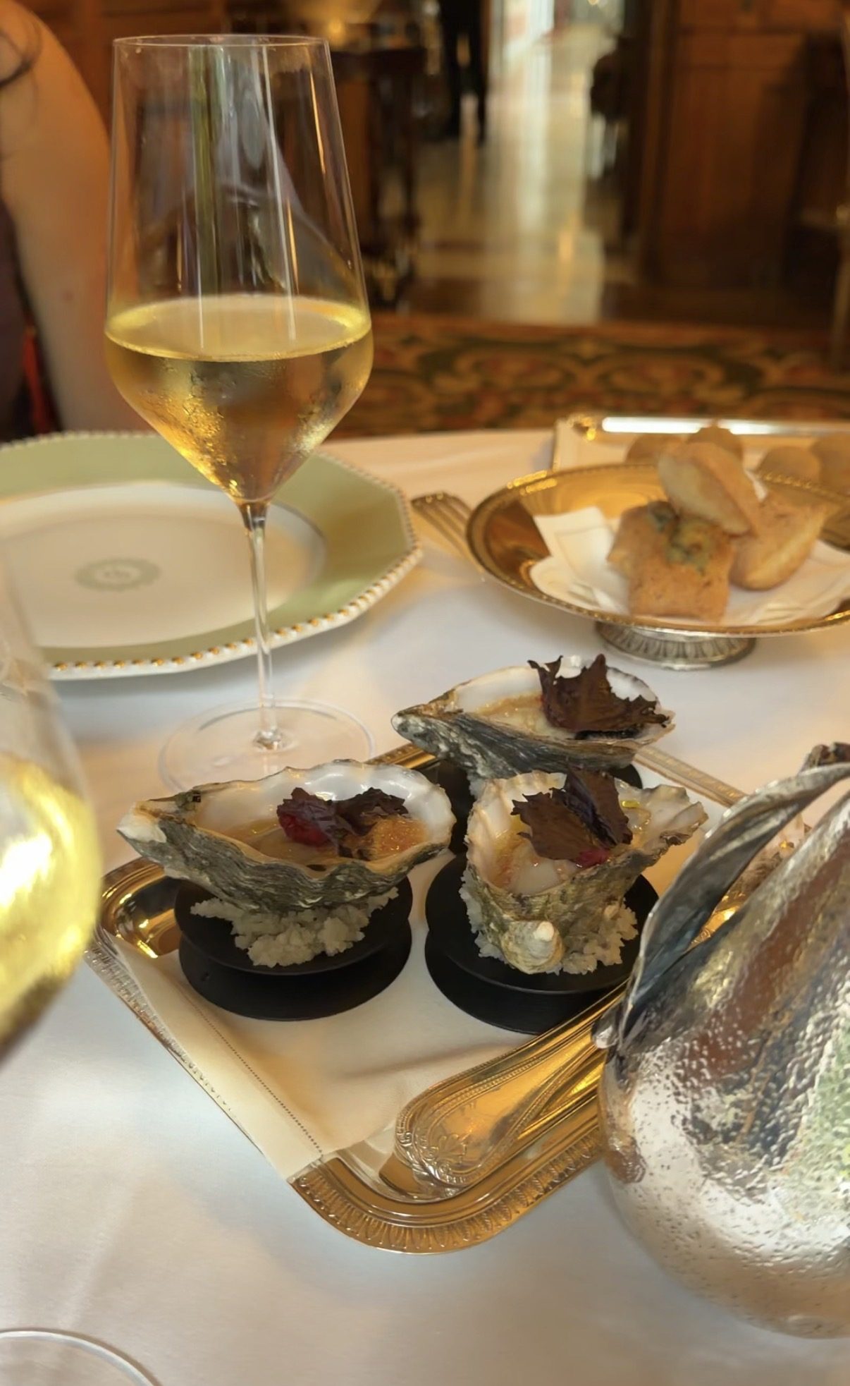 Three oysters on a gold tray with champagne at Le Clarence in Paris