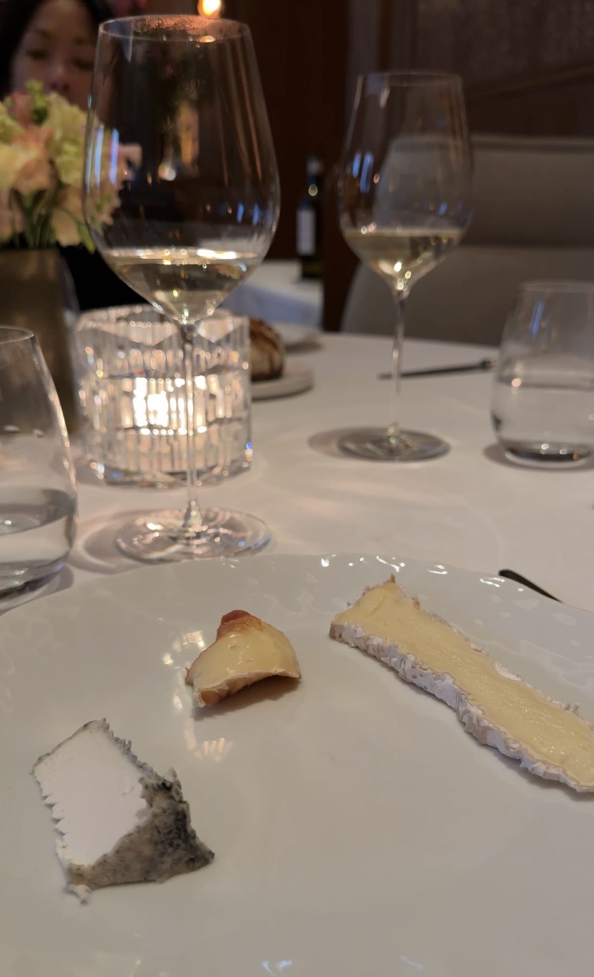 Three cheeses from the Le Taillevent cheese trolley, with wine glasses behind the plate