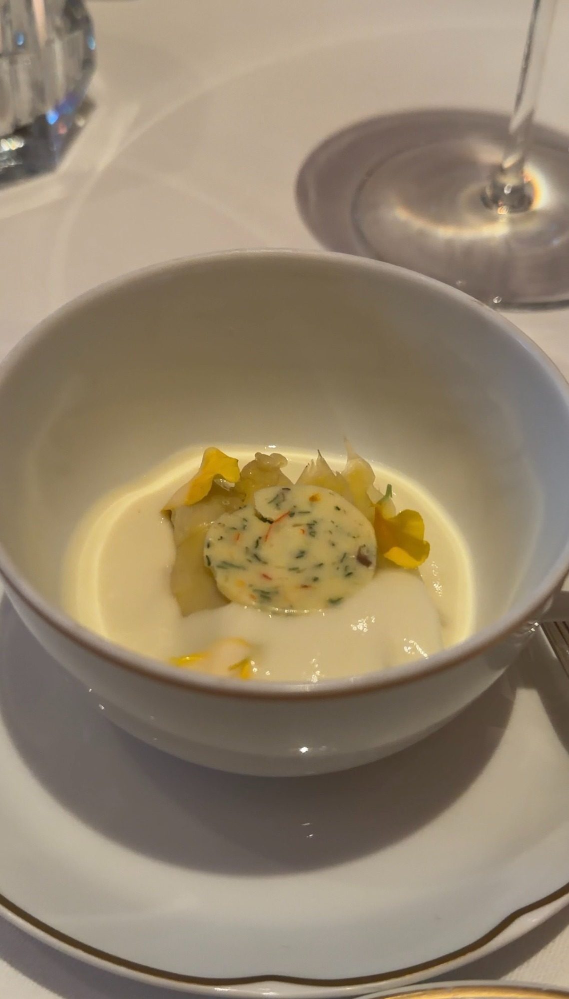 Cream sauce with a herb-flecked round and yellow flowers at Le Taillevent