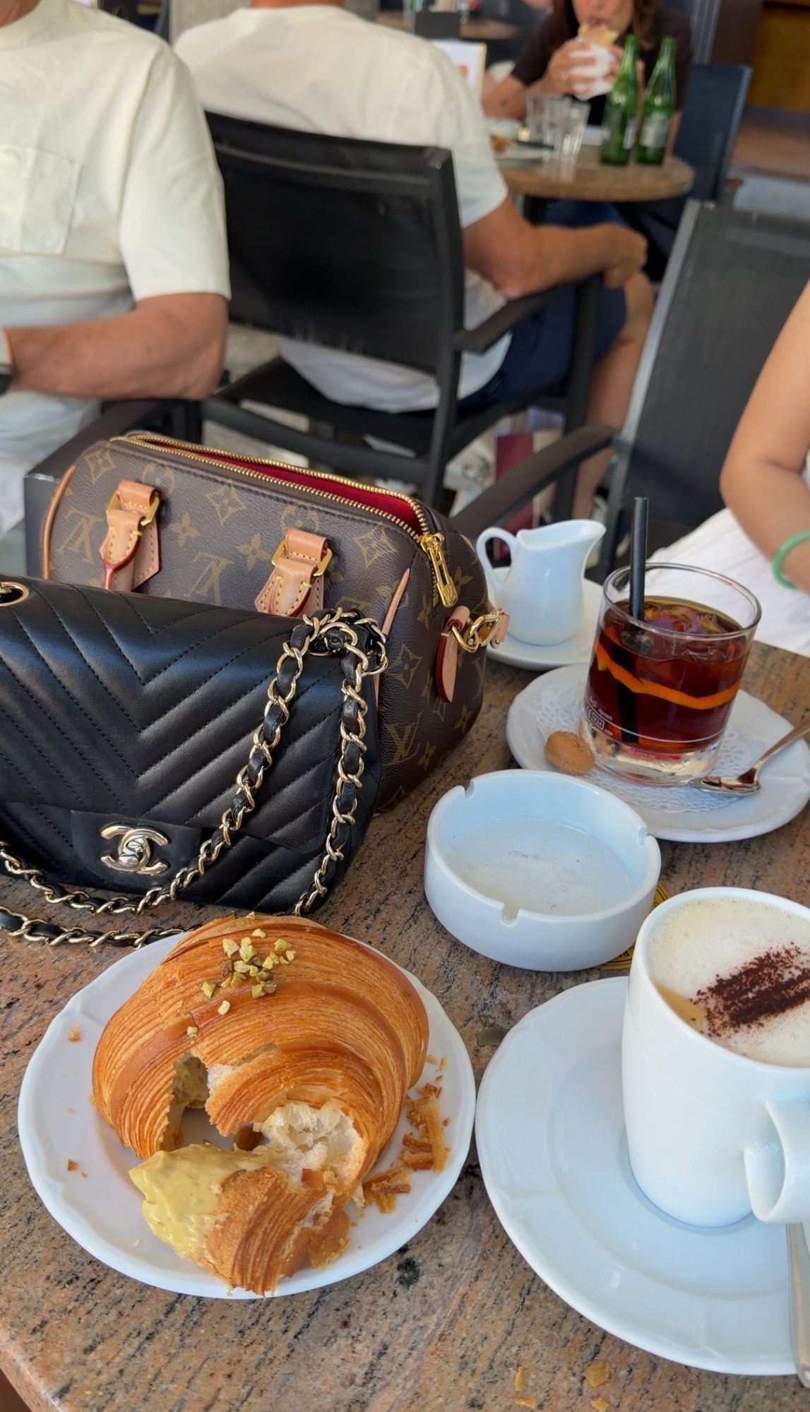 Pistachio croissant and cappuccino at a cafe table in Locarno