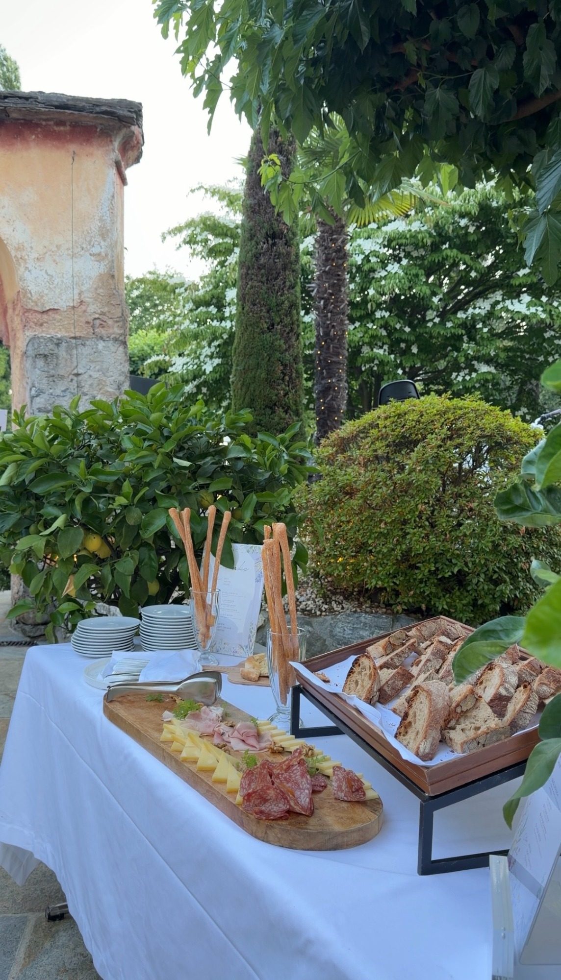 Outdoor antipasti in Locarno with bread, cheese, cured meat, and lemon trees