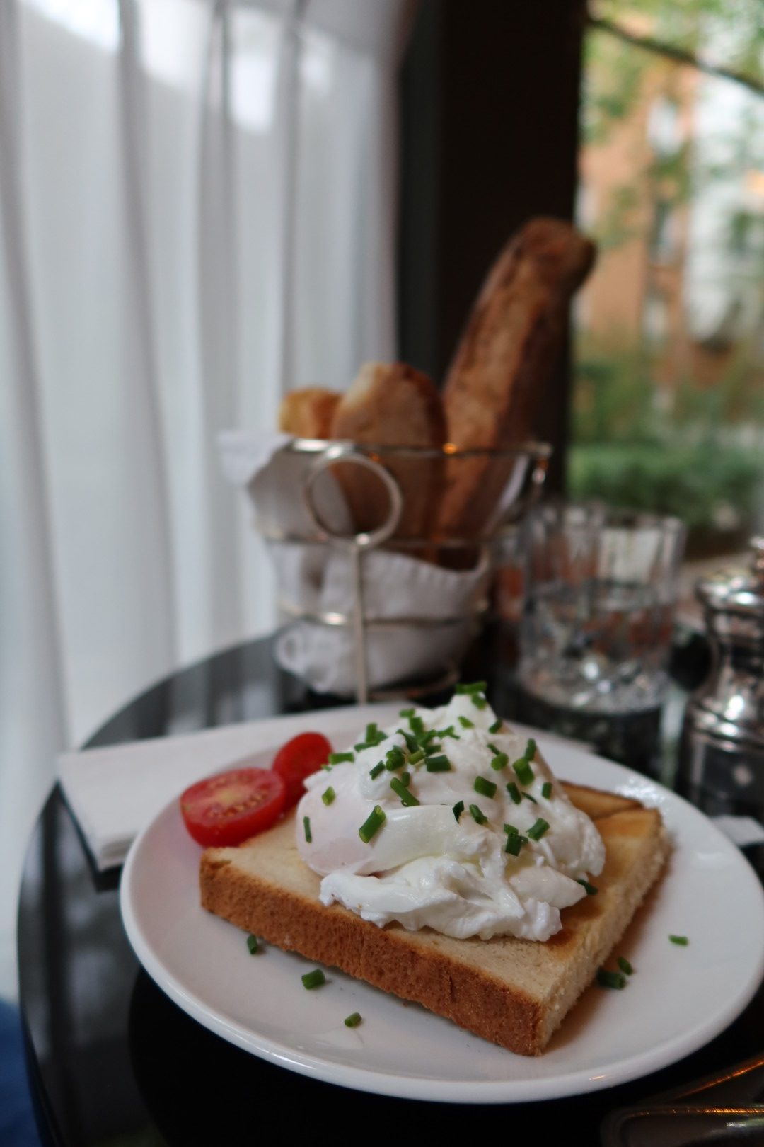 Poached egg on toast with chives and tomato at a Paris breakfast table