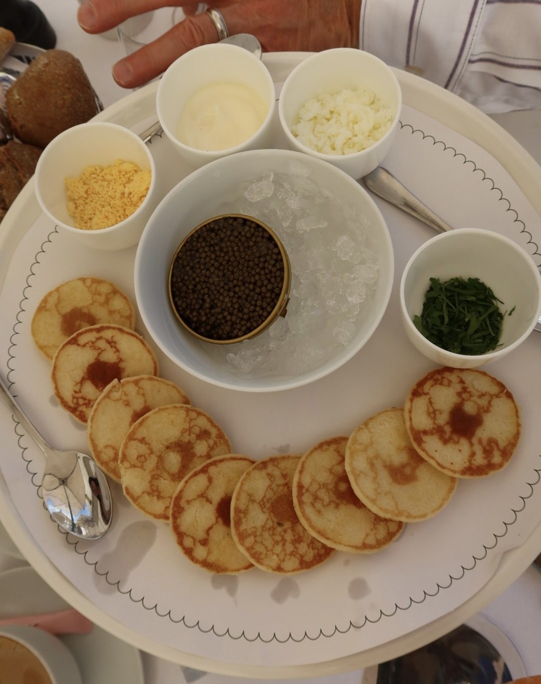 Blinis served with caviar on ice, crème fraîche, egg yolk, and chives in Paris