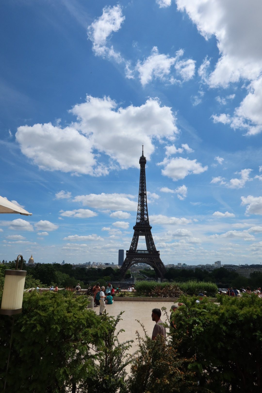 The Eiffel Tower rising over Paris on a bright afternoon, seen from a terrace above the city