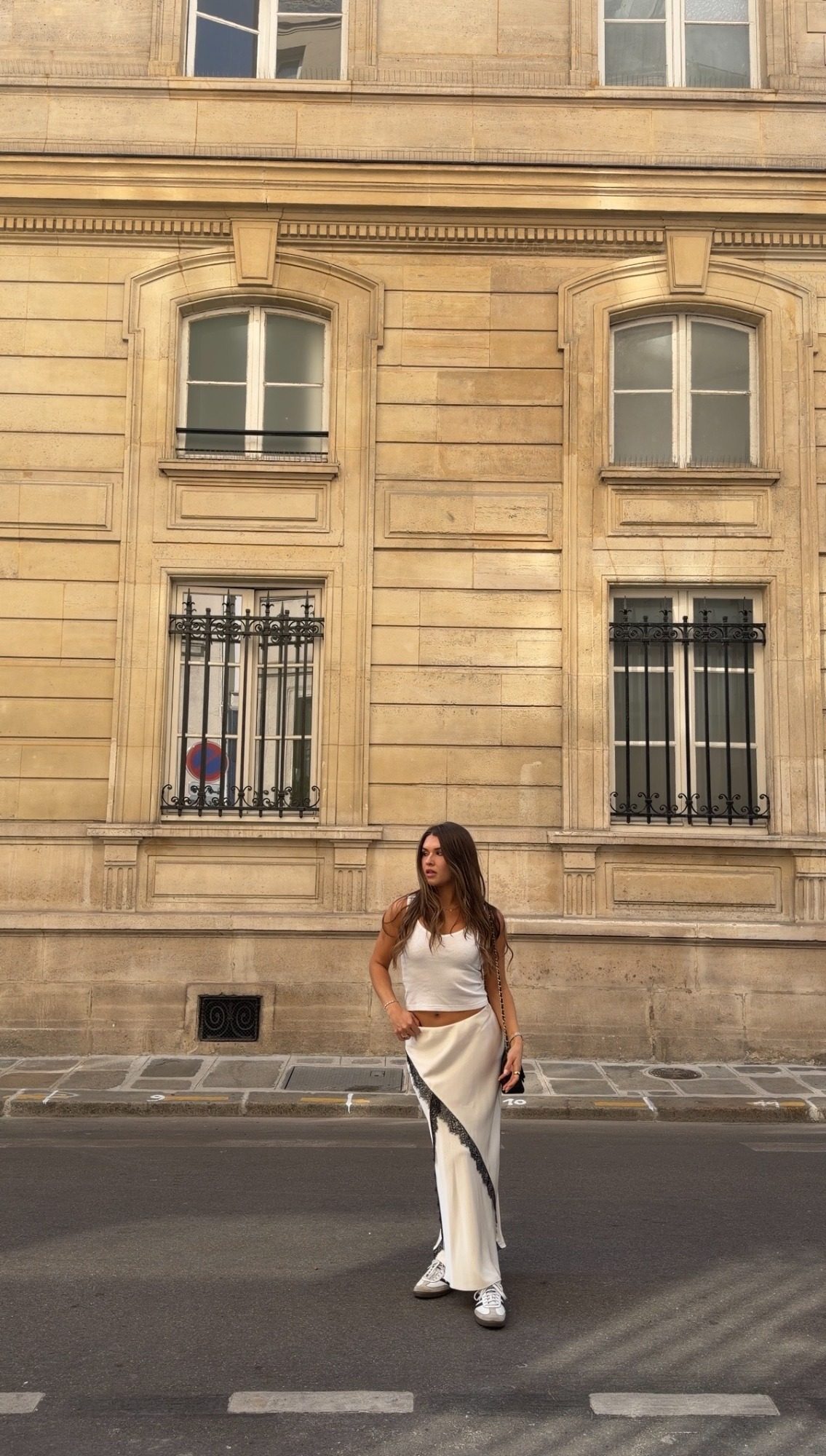 Jess in a white top and satin skirt standing in front of a limestone building in Paris
